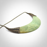 This picture shows a hand carved New Zealand flower jade contemporary half-shield pendant. It is a light green colour and is a wonderful, large piece of jewellery. The cord is hand plaited and adjustable so that you can position the pendant where it suits you best. This piece was carved for us by Donna Summers.